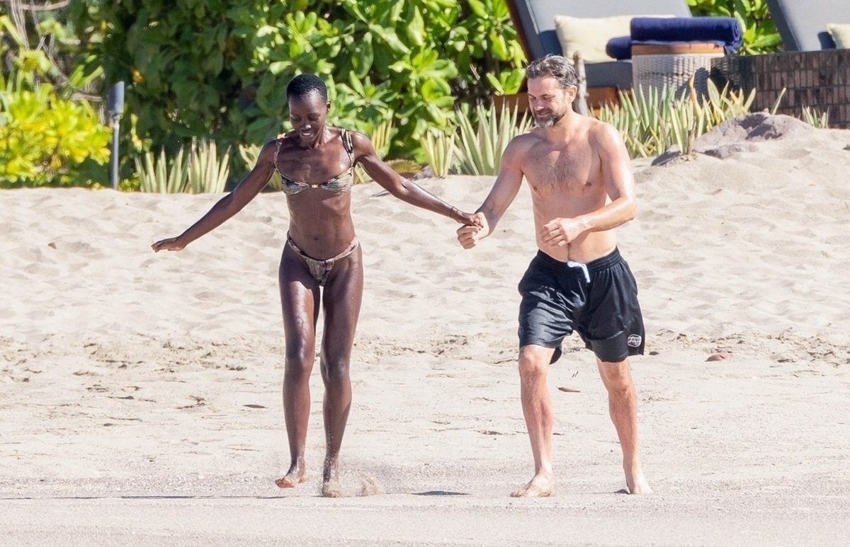 Joshua Jackson și Lupita Nyong'o se plimbă pe plajă ținându-se de mână