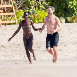 Joshua Jackson și Nyong'o în timp ce aleargă pe plajă ținându-se de mână