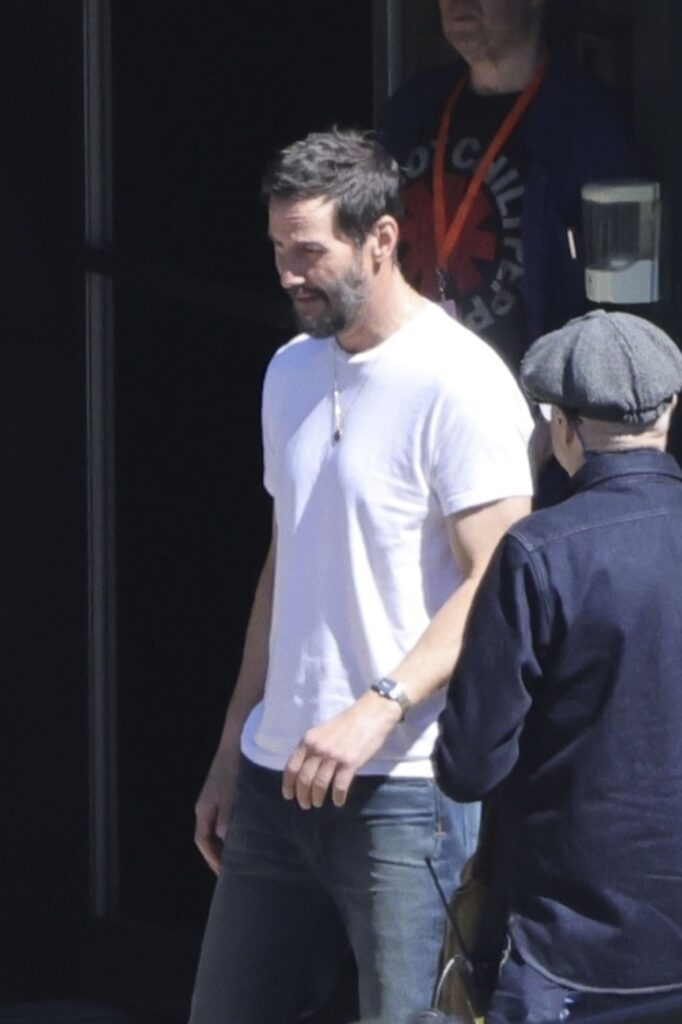 Keanu Reeves într-un tricou alb și o pereche de blugi în timp ce filmează pentru Outcome