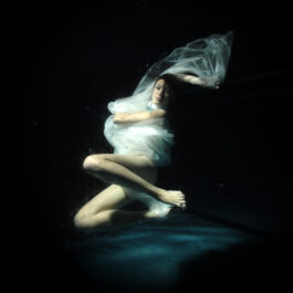 O femeie într-o rochie albă, care se scufundă în apă
