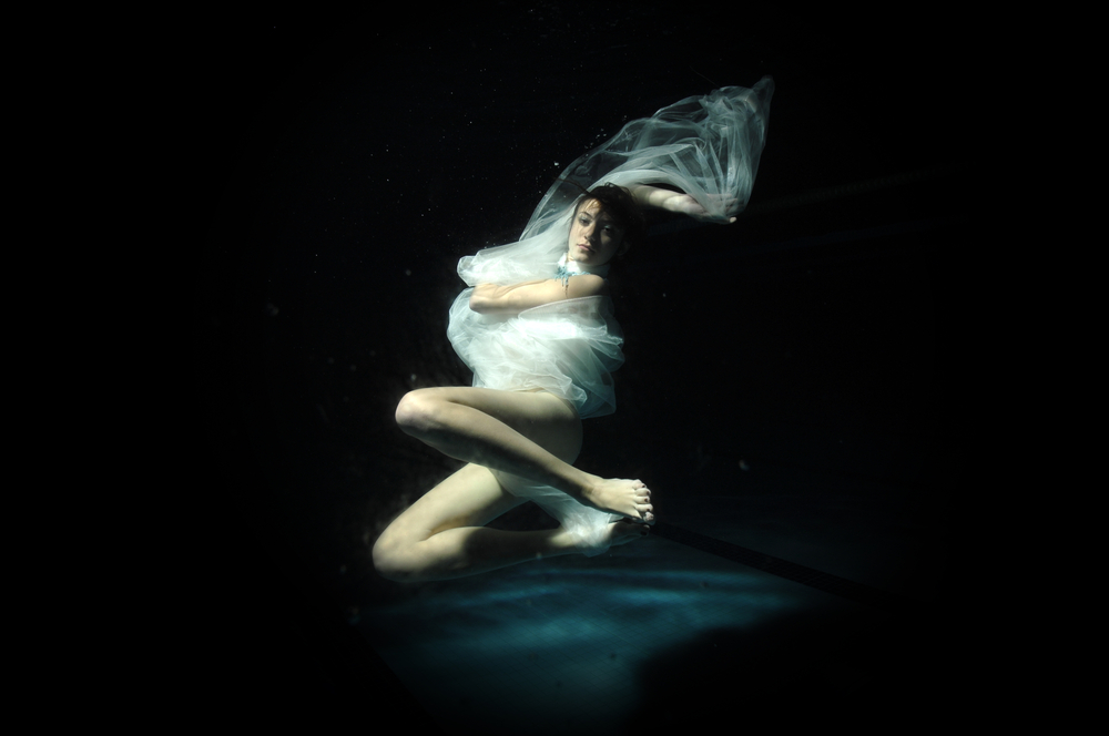 O femeie într-o rochie albă, care se scufundă în apă