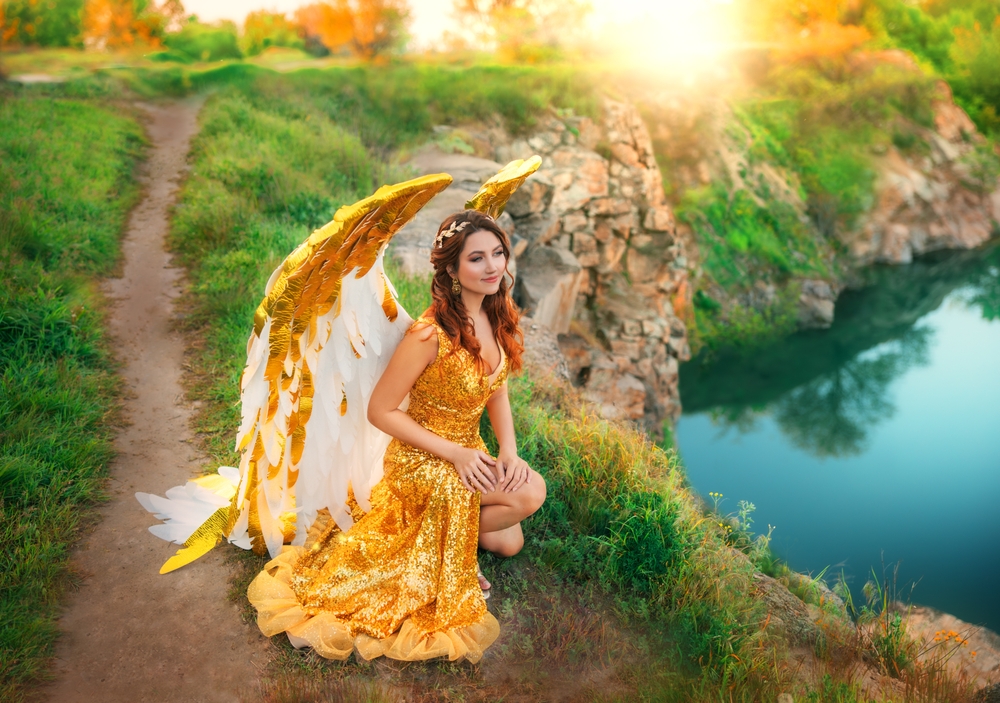 O femeie în rochie aurie, cu aripi de înger în spate