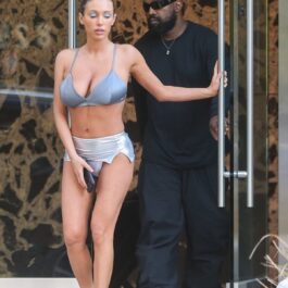 Bianca Censori într-un costum de baie argintiu alături de Kanye West care poartă un costum negru