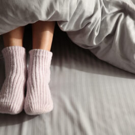 O femeie care stă cu șosete roz în picioare, în pat