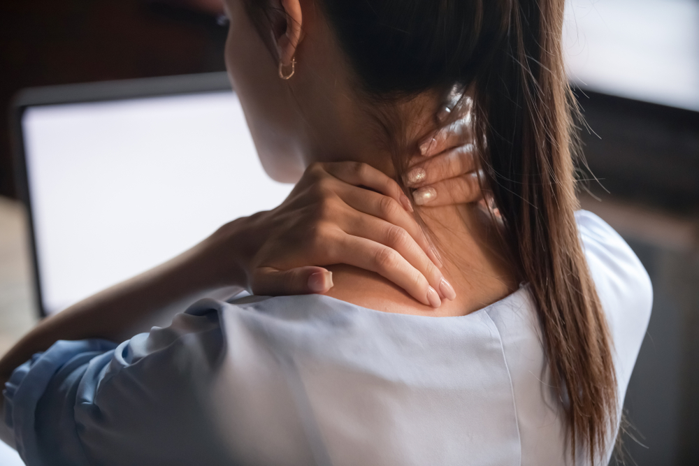 O femeie care se confruntă cu dureri de spate în zona gâtului