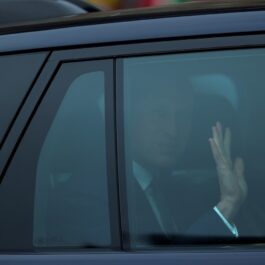 Prințul William face cu mâna fotografilor, din mașină