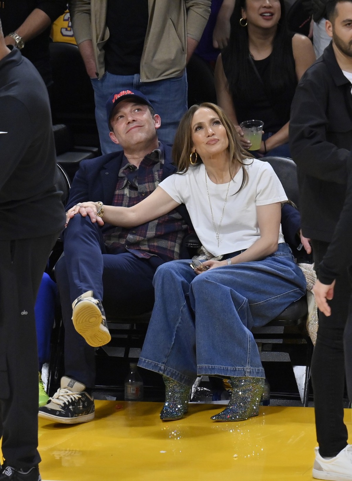 Jennifer Lopez stând cu mânna pe piciorul lui Ben Affleck în timpul unui meci de baschet