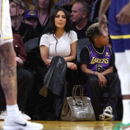 Kim Kardashian în timp ce participă la un meci de baschet și își ține geanta pe jos