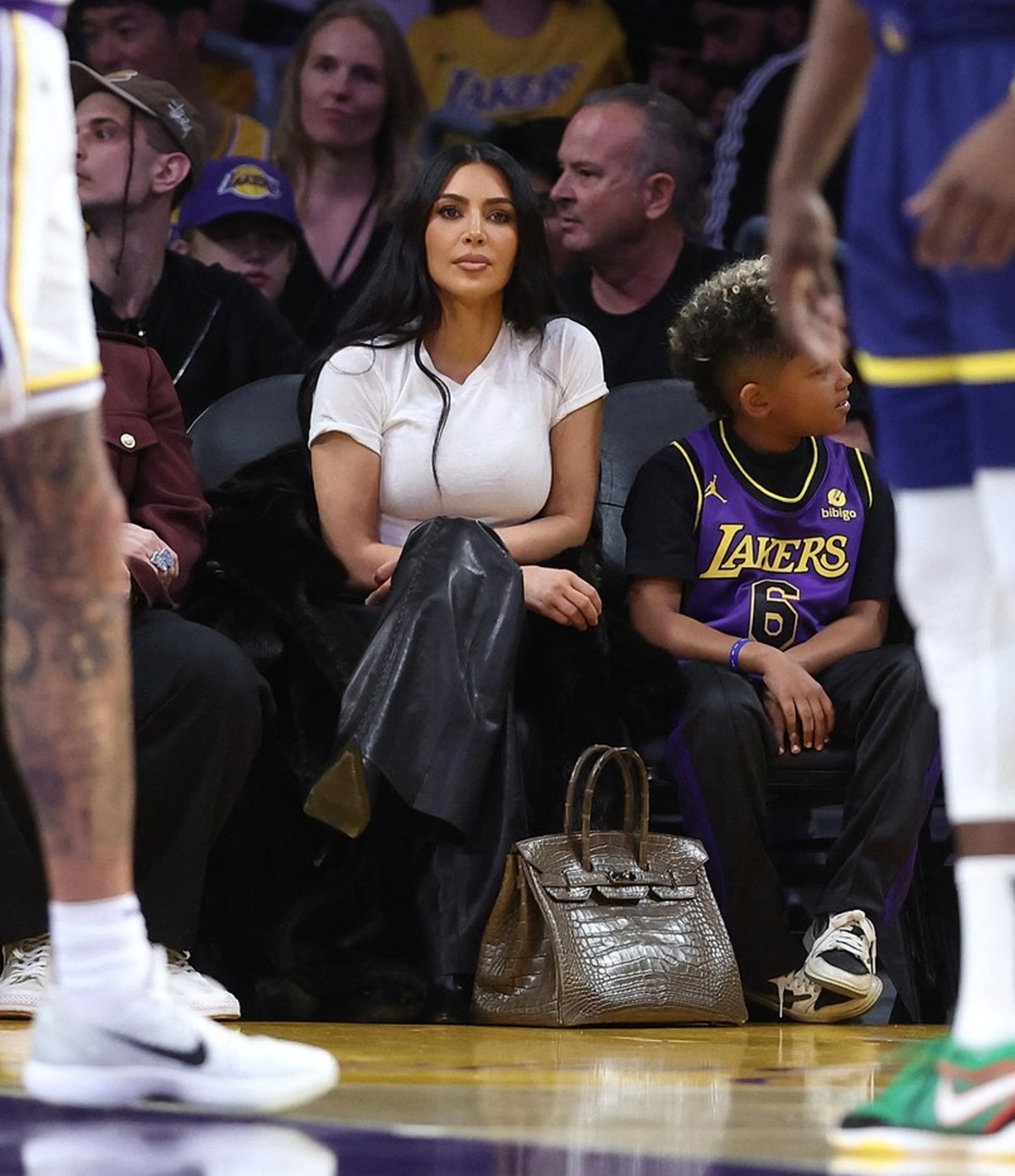 Kim Kardashian în timp ce participă la un meci de baschet și își ține geanta pe jos
