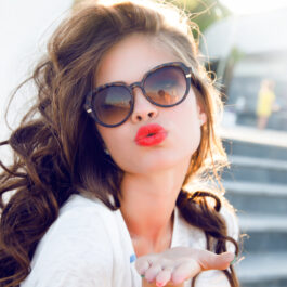 O femeie tânără cu ochelari de soare la ochi și un ruj portocaliu pe buze