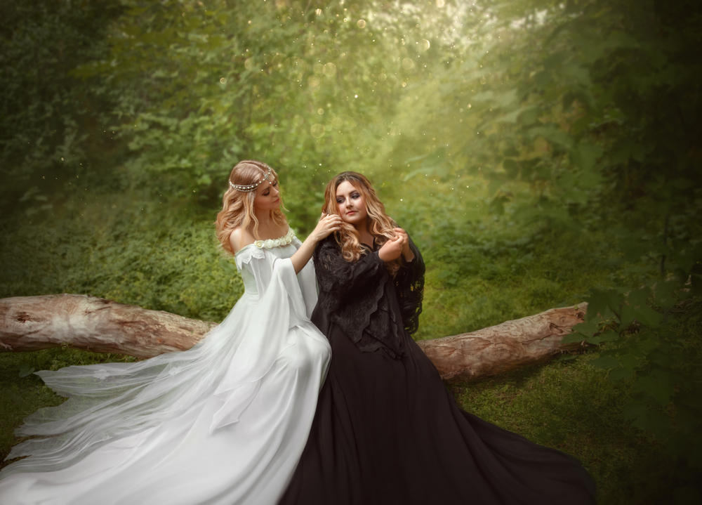 Două femei îmbrăcate în rochii lungi, albă și neagră