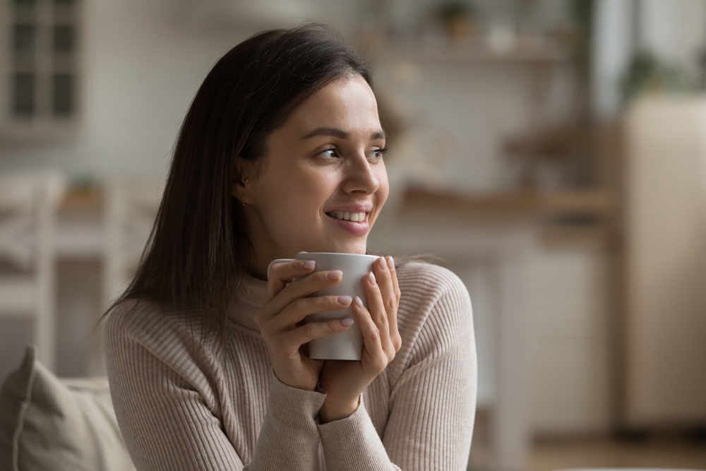 O femeie fericită că bea o ceașcă cu cafea