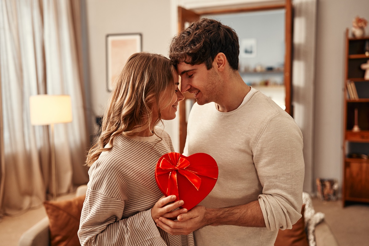 Un cuplu de îndrăgostiți care își oferă o cutie de ciocolată în formă de inimioară