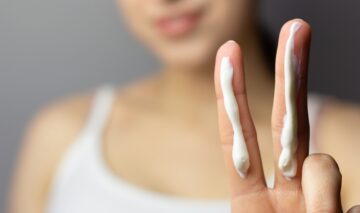 O femeie care are cremă solară aplicată pe două degete