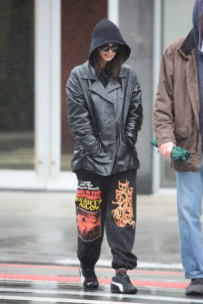 Emily Ratajkowski în timp ce se plimbă prin ploaie și poartă o glugă pe cap