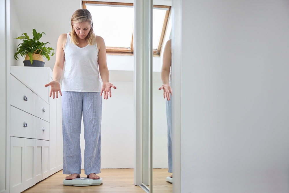 O femeie la menopauză care nu înțelege kilogramele de pe cântar