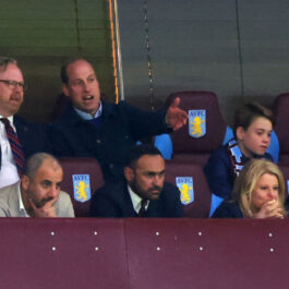 Prințul William discută cu un bărbat în tribune la un meci de fotbal