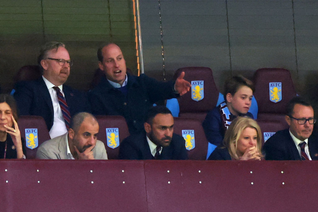 Prințul William discută cu un bărbat în tribune la un meci de fotbal