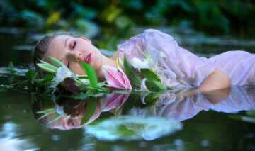 O femeie într-o rochie albă, care plutește cu o floare pe luciul apei