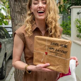 Amber Heard cu zâmbetul pe buze, cu un cadou în mână