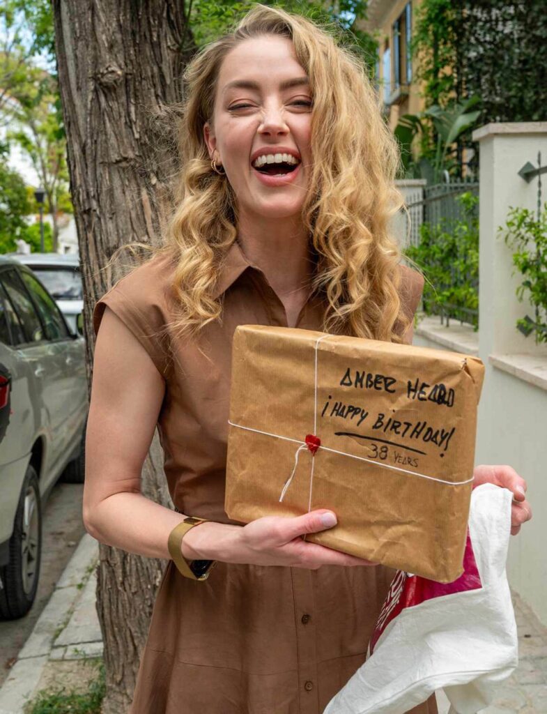 Amber Heard cu zâmbetul pe buze, cu un cadou în mână