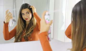 O femeie tânără care își aplică șampon uscat pe scalp