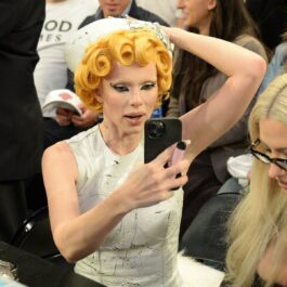 Julia Fox cu părul orange în timp ce se uită la un telefon și se pozează