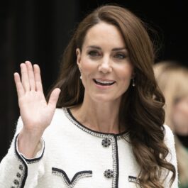Kate Middleton într-un costum alb în timp ce face cu mâna publicului
