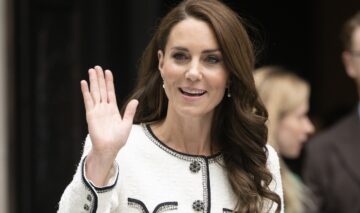 Kate Middleton într-un costum alb în timp ce face cu mâna publicului