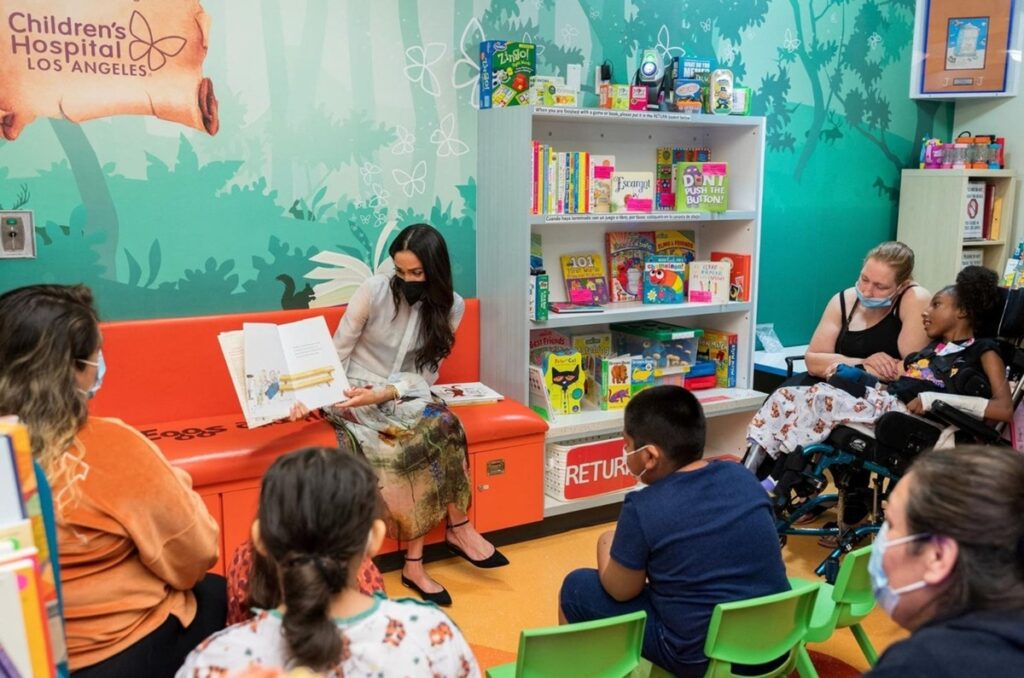 Meghan Markle în timp ce le arată o carte de copiii micuților din spitalul de copii din Los Angeles