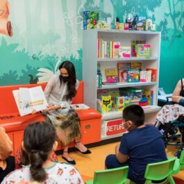 Meghan Markle în timp ce le arată o carte de copiii micuților din spitalul de copii din Los Angeles