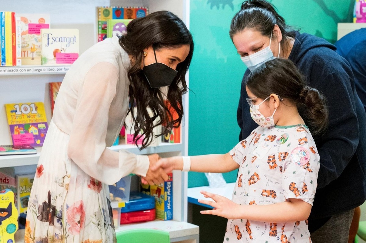 Meghan Markle în timp ce dă mâna cu o fetiță de la spitalul de copii din Los Angeles