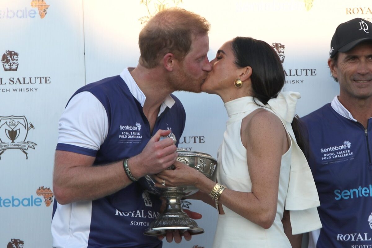 Meghan Markle și Prințul Harry în timp ce se sărută cu un trofeu de polo în brațe