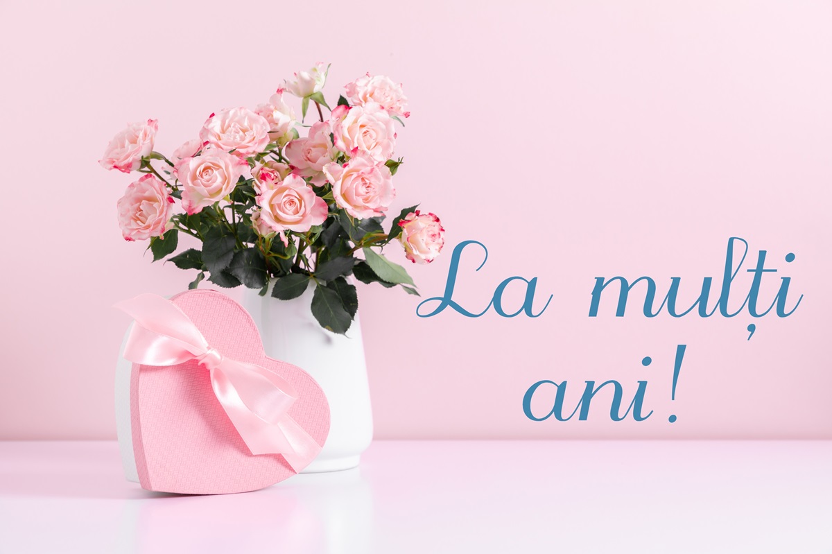 Un fundal roz pe care se află o vază cu trandafiri roz și o cutie de bomboane pentru a ilustra mesajele de Florii 2024