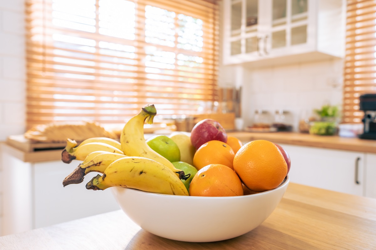 O masă pe care se află un castron alb cu portocale, mere și banane