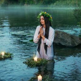 O femeie frumoasă care poartă o rochie albă și stă într-un lac pentru a ilustra una dintre acele zodii nefericite a lunii mai 2024