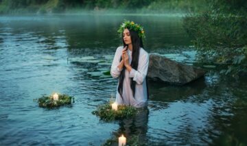 O femeie frumoasă care poartă o rochie albă și stă într-un lac pentru a ilustra una dintre acele zodii nefericite a lunii mai 2024