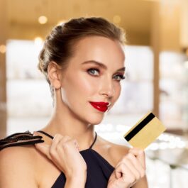O femeie frumoasă care ține în mână un card de credit pentru a ilustra una dintre acele zodii care ar renunța la oamenii dragi pentru bani