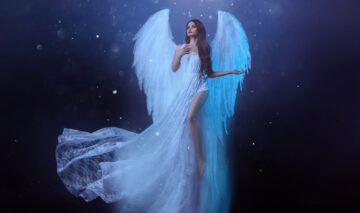 O femeie îmbrăcată în rochie albă, cu aripi de înger