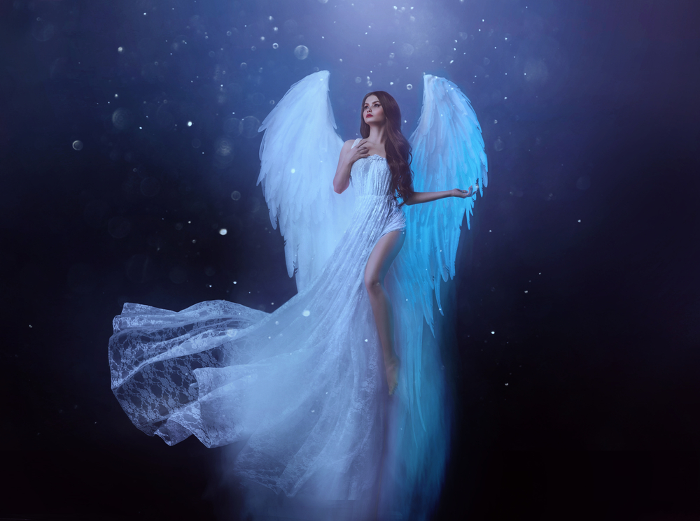 O femeie îmbrăcată în rochie albă, cu aripi de înger