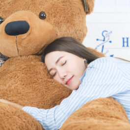 O femeie care doarme pe un urs mare din pluș