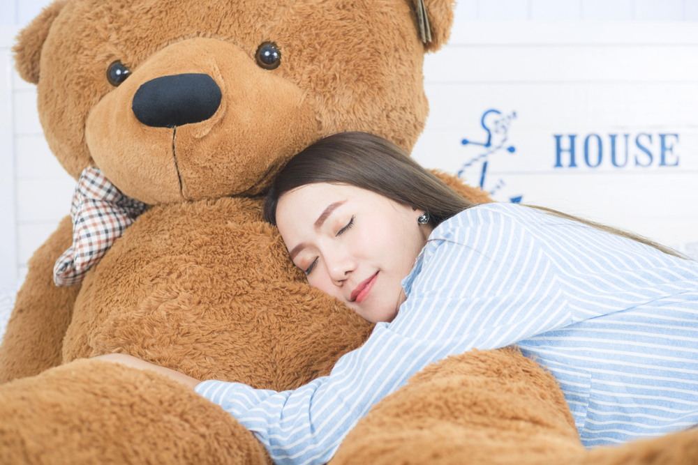 O femeie care doarme pe un urs mare din pluș