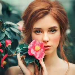 O femeie frumoasă care ține un trandafir alături de fața sa pentru a ilustra una dintre acele zodii pe care vei regreta dacă le vei pierde din viața ta