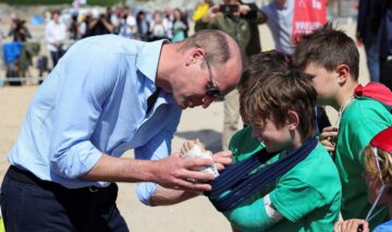 Prințul William semnează ghipul unui copil