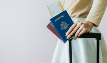 O femeie cu un bagaj și două pașapoarte în mână
