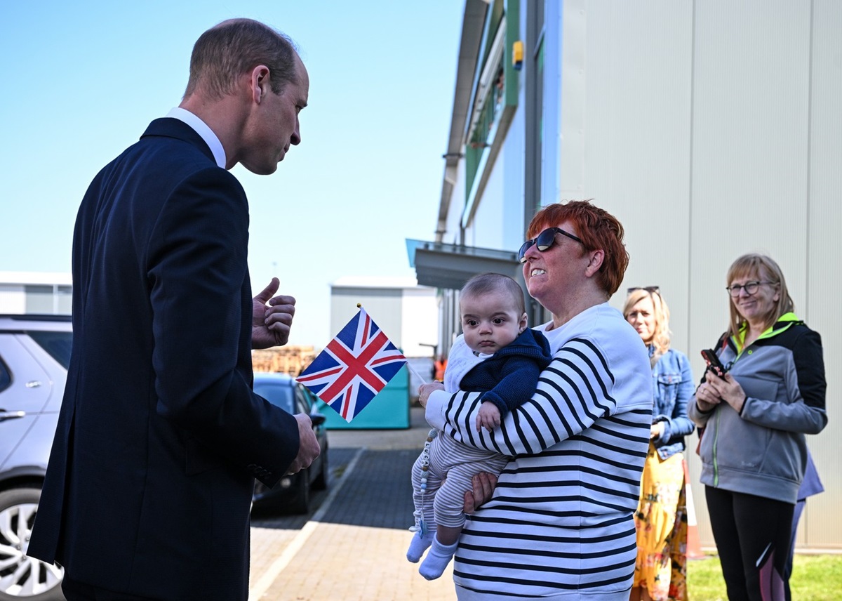 Prințul William în timp ce vorbește cu o femeie care ține un bebeluș în brațe
